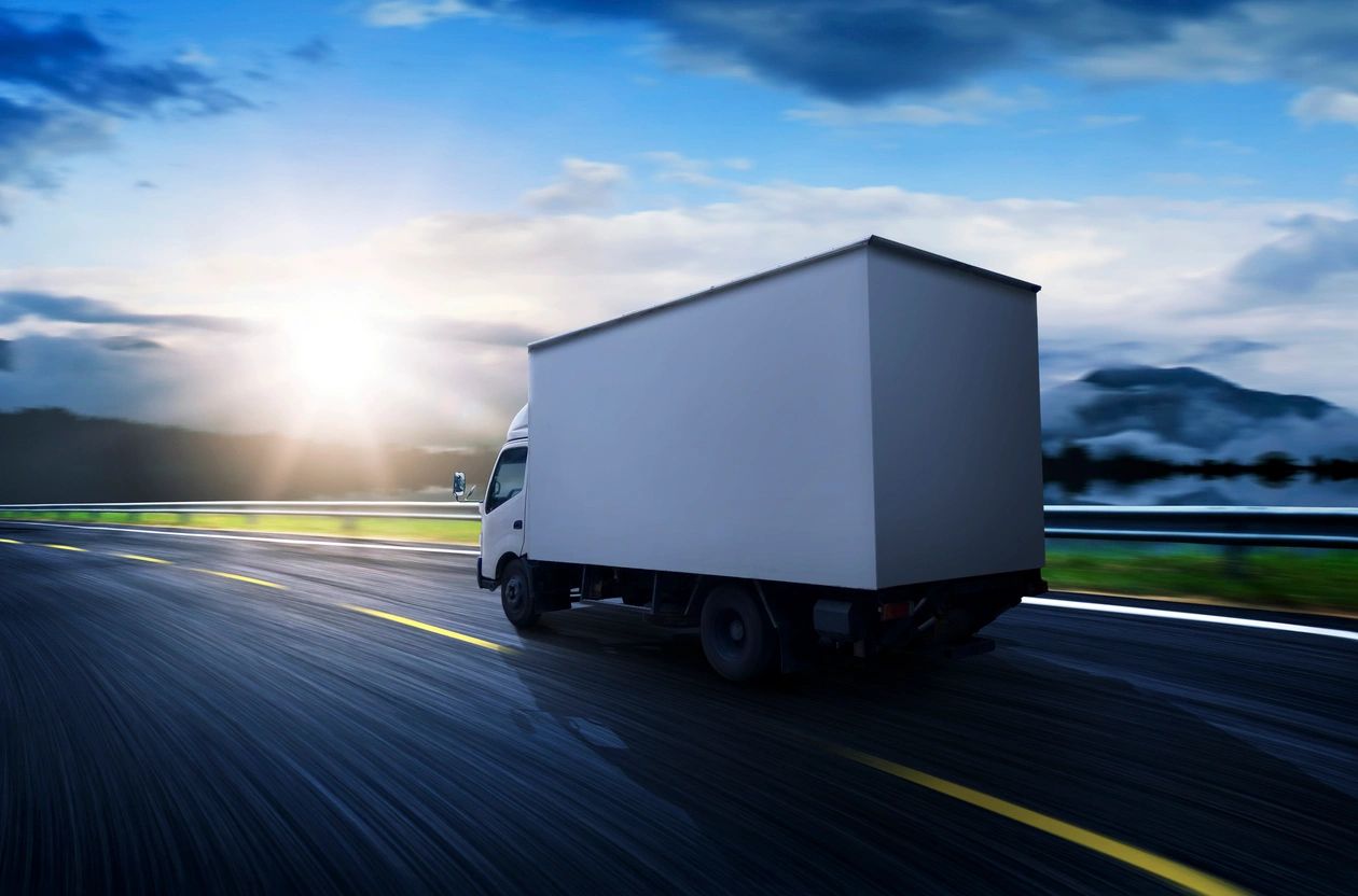A truck driving down the road with a sky background